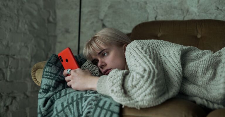 ragazza triste scorre immagini sullo smartphone