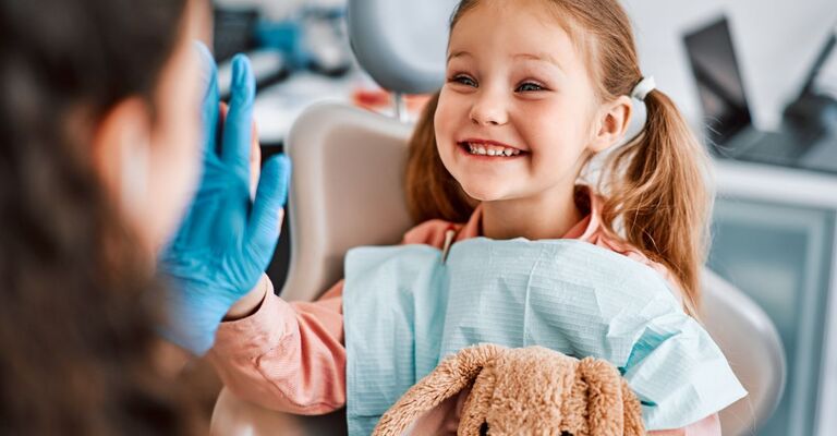 Una bambina sorridente batte il cinque al dentista