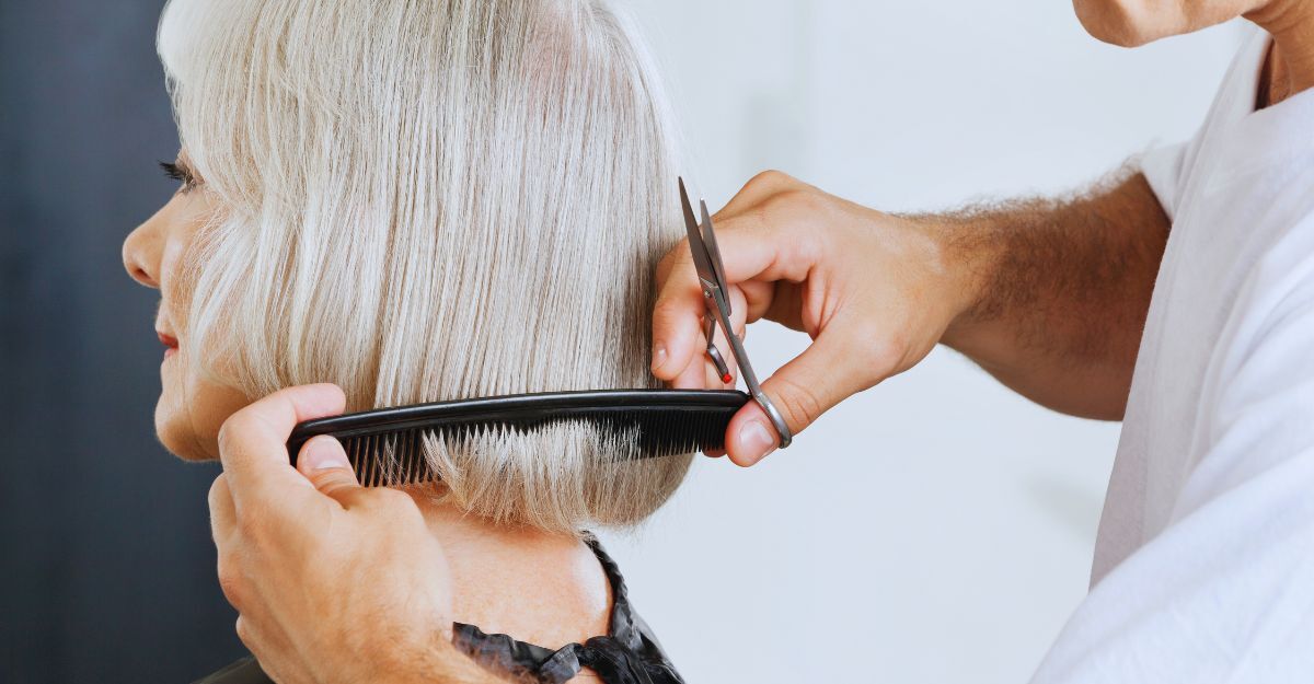 Parrucchiere che aggiusta il taglio corto di una signora coi capelli bianchi