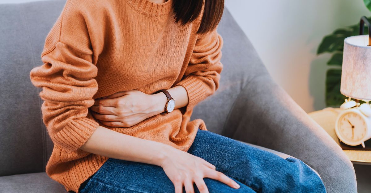 Una donna seduta sul divano si tiene la mano sul fianco