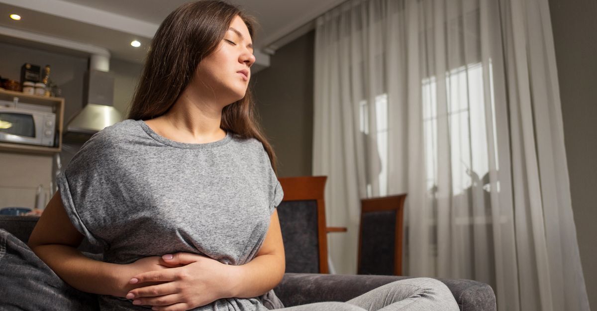 ragazza seduta sul divano si tiene la pancia