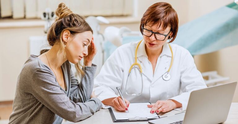Paziente che si confronta con la sua ginecologa leggendo la cartella medica