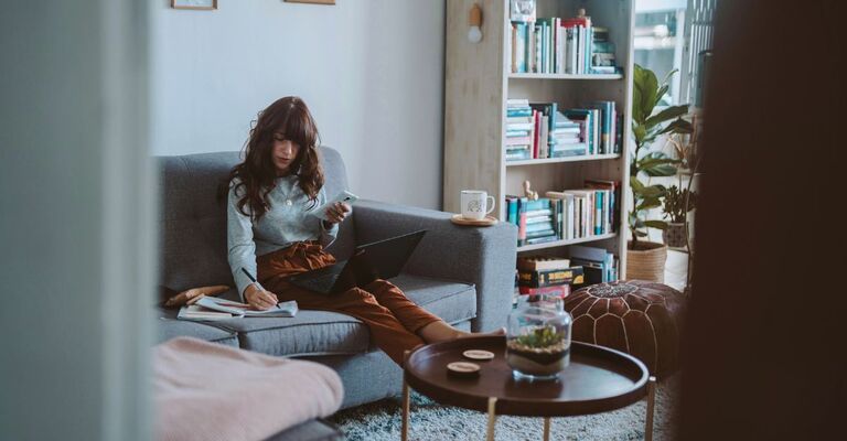 Giovane donna seduta sul divano che pianifica la giornata