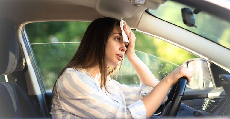 Una donna si asciuga il sudore in fronte mentre è in macchina