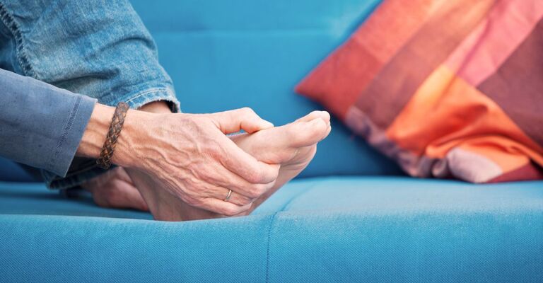 Persona che tocca l’avampiede dolorante, sintomo tipico della metatarsalgia