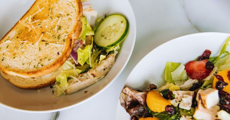 Ricette economiche estive: piatti veloci, freschi e gustosi Due piatti con panino con verdure e un altro piatto con insalata di frutta e verdure