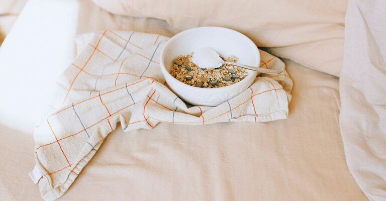 Ciotola con cereali e yogurt su un canovaccio poggiato su un letto al sole