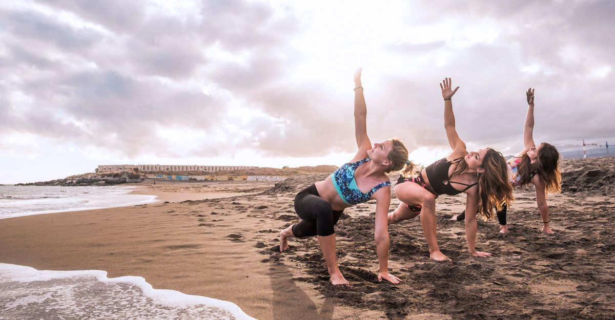 Tre donne si allenano in spiaggia al tramonto