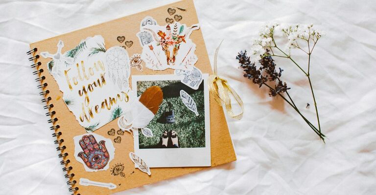 Notebook con la copertina decorata con fotografie e scritte appoggiato sul letto