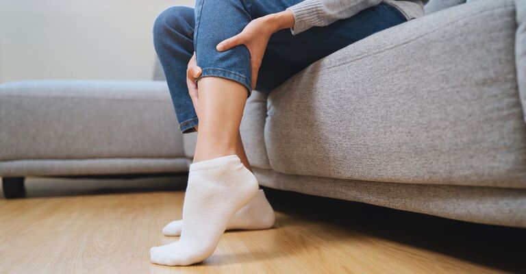 Persone che massaggia la gamba seduta sul divano