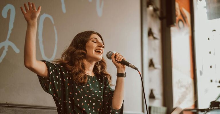 Ragazza che canta su un palco a occhi chiusi col microfono