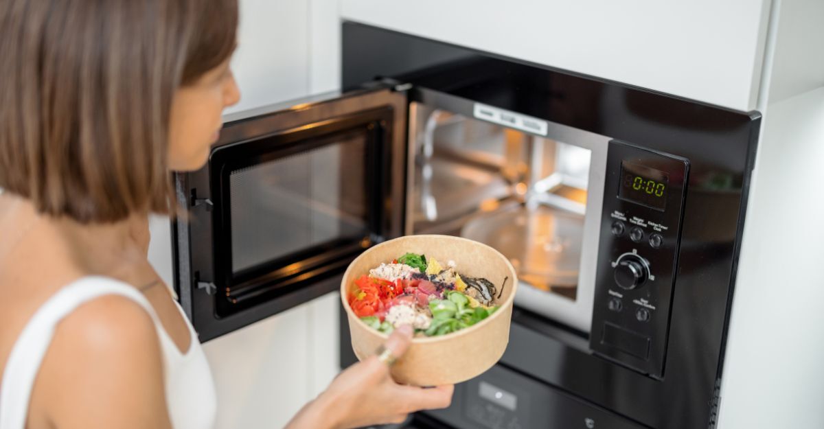 donna inserisce cibo nel forno a microonde