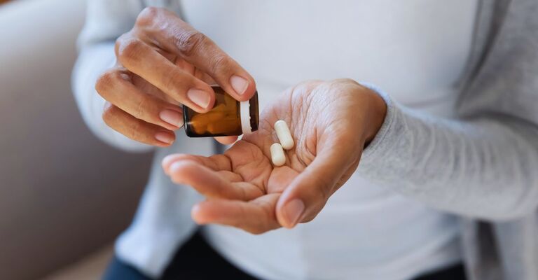 Primo piano di due mani, in cui una versa delle capsule sull'altra mano