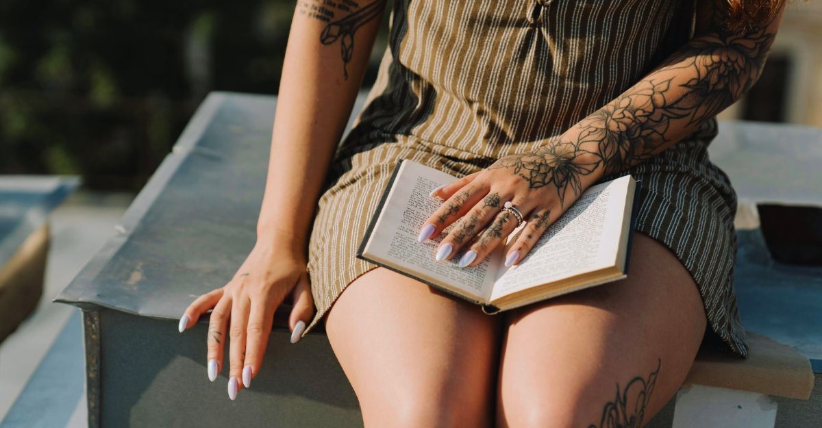 Primo piano di una ragazza tatuata che legge al sole