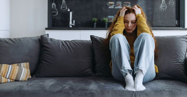 Ragazza sul divano con le mani nei capelli