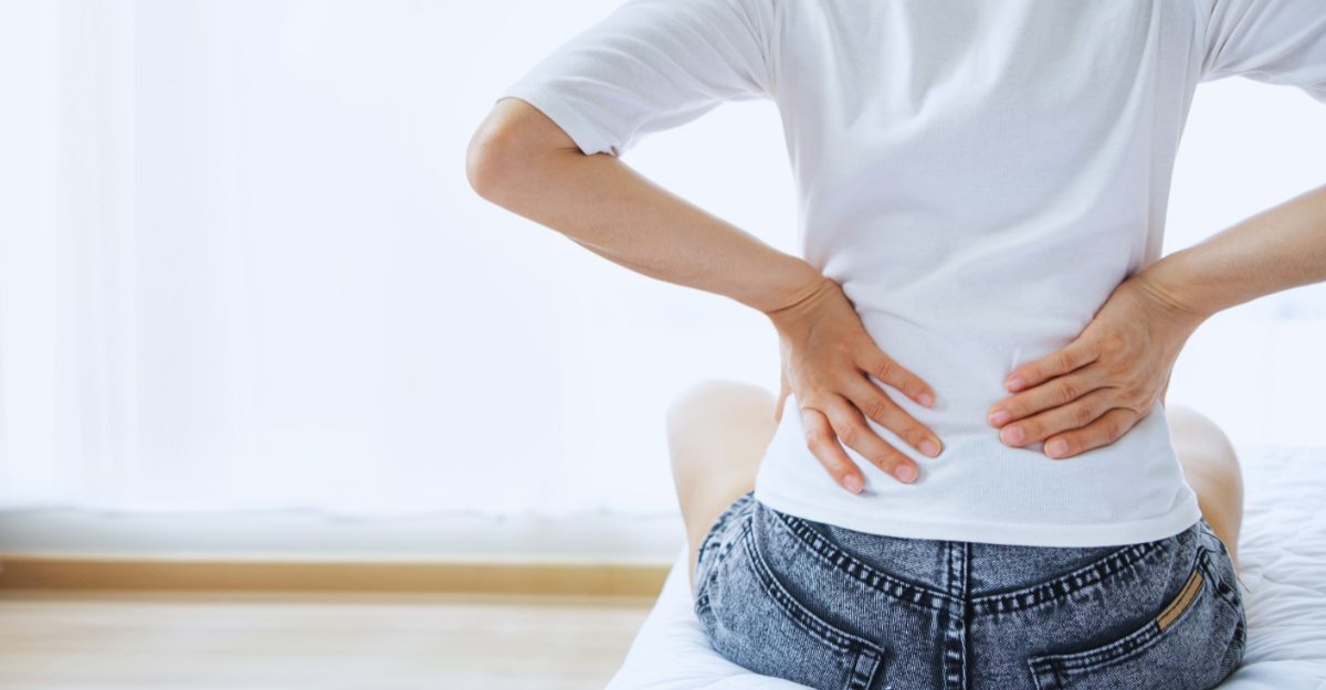 Donna di spalle con le mani all'altezza del coccige per un fastidio