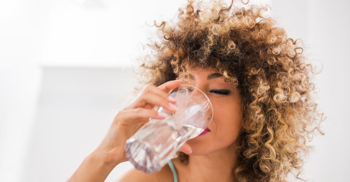 donna beve un grosso bicchiere d'acqua