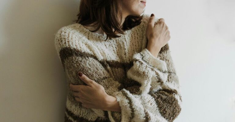 Una persona indossa un maglione a righe e si abbraccia