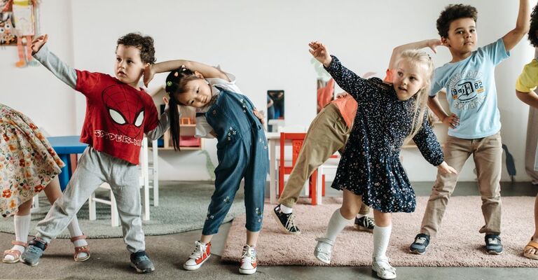 Bambini piccoli in fila che fanno un esercizio o un passo di danza.