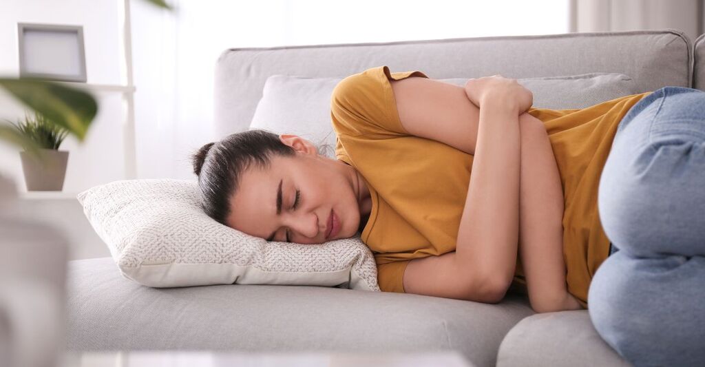 ragazza sdraiata sul divano si tiene la pancia