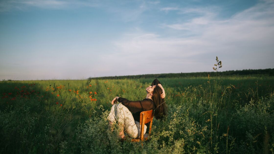 Donna distesa su una sedia in un campo fiorito.