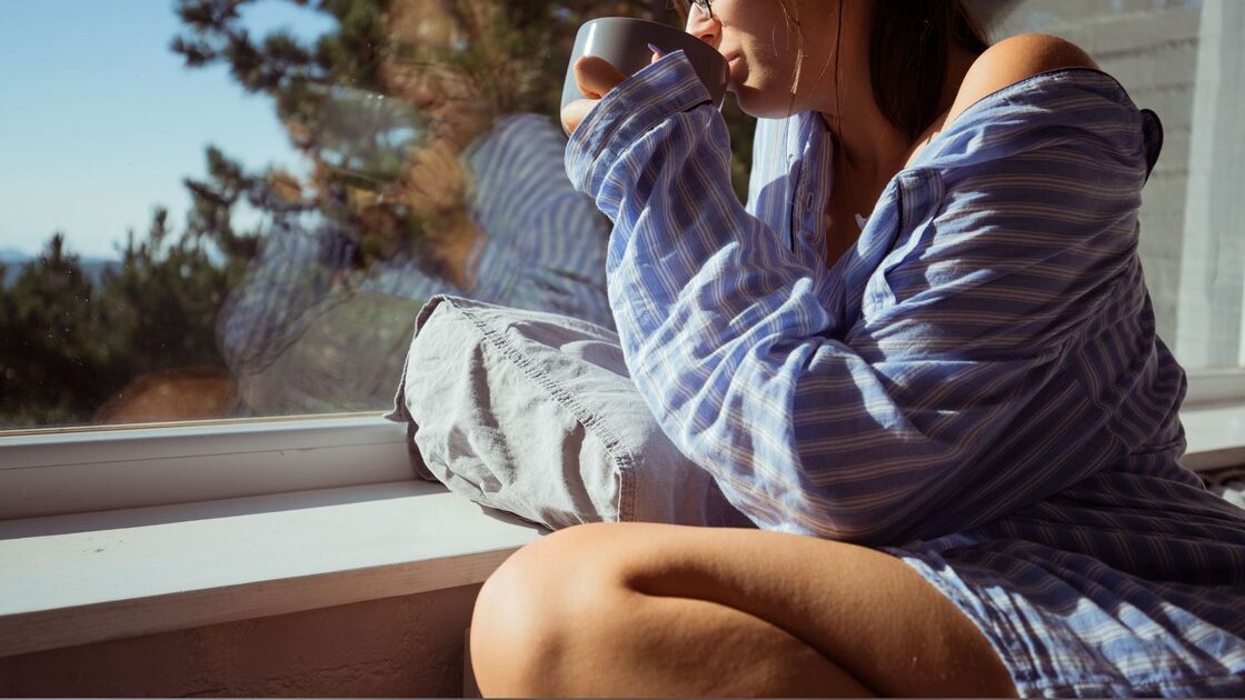 Una persona si gode una bevanda calda vicino a una finestra.