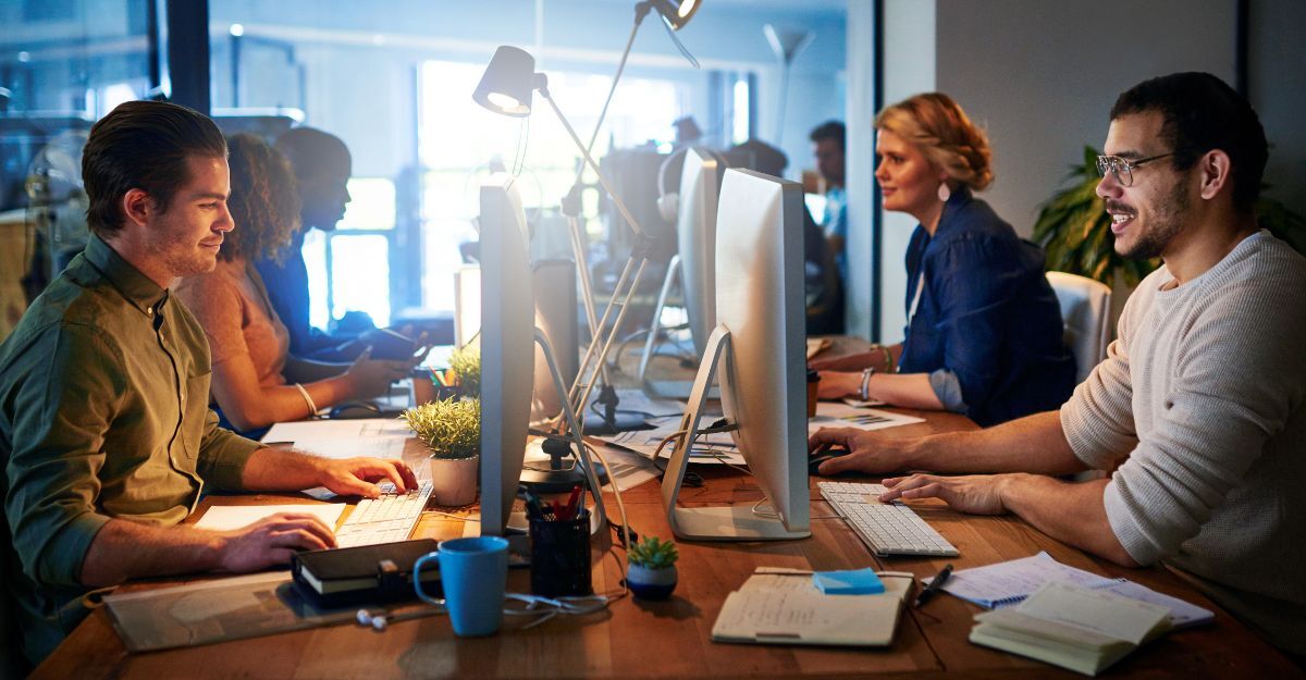 Primo piano di un gruppo di persone sorridenti che lavorano su computer in un ufficio moderno
