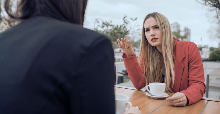 De donne che discutono davanti a un caffè.