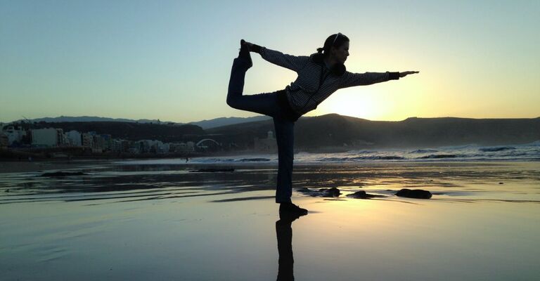 Una donna che pratica Yoga su una spiaggia.