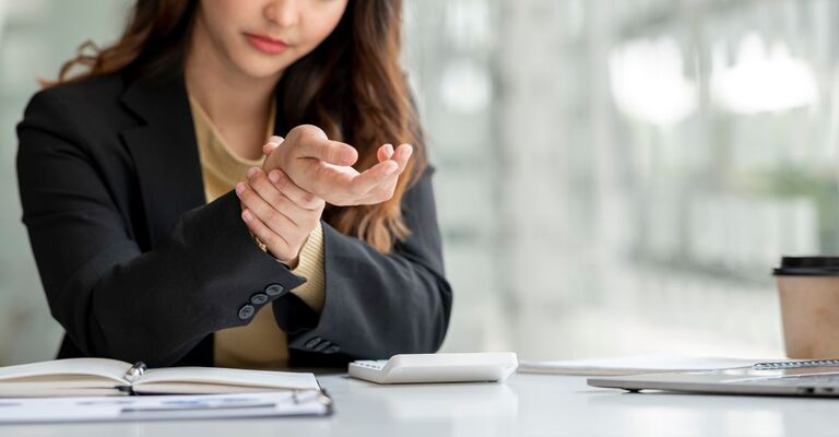 donna al computer si tiene il polso dolorante