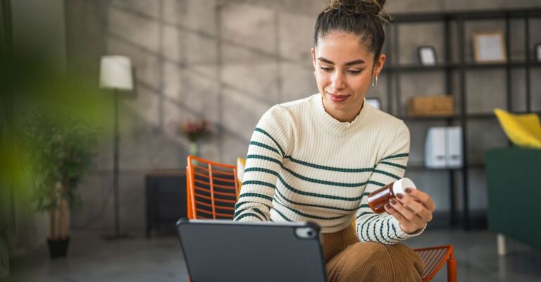 ragazza al pc tiene in mano confezione di integratori