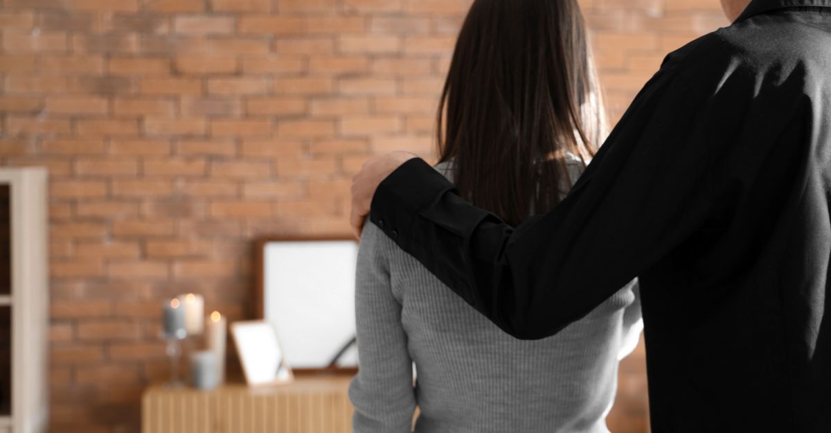 Una donna in lutto viene consolata da un uomo.