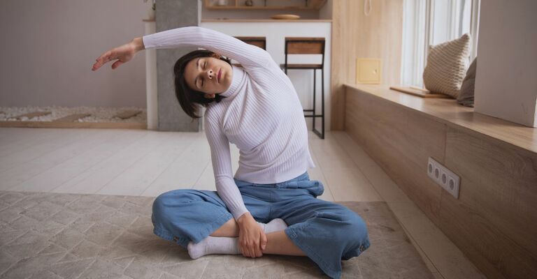Una donna esegue un esercizio di stretching a casa.