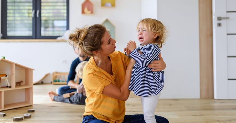 Mamma che calma la figlia piccola mentre piange nella sua cameretta