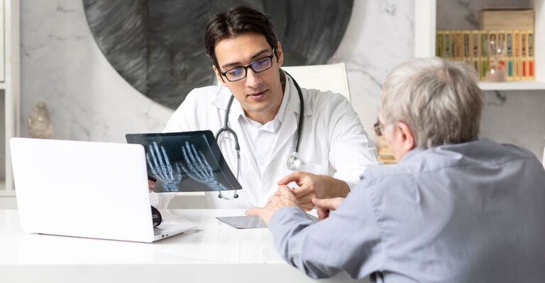 Dottore che mostra le lastre della mani alla paziente anziana nel suo studio