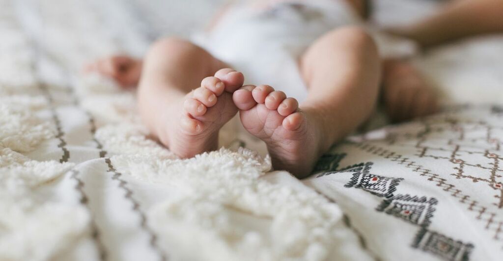 Primo piano dei piedi di un neonato su un copriletto