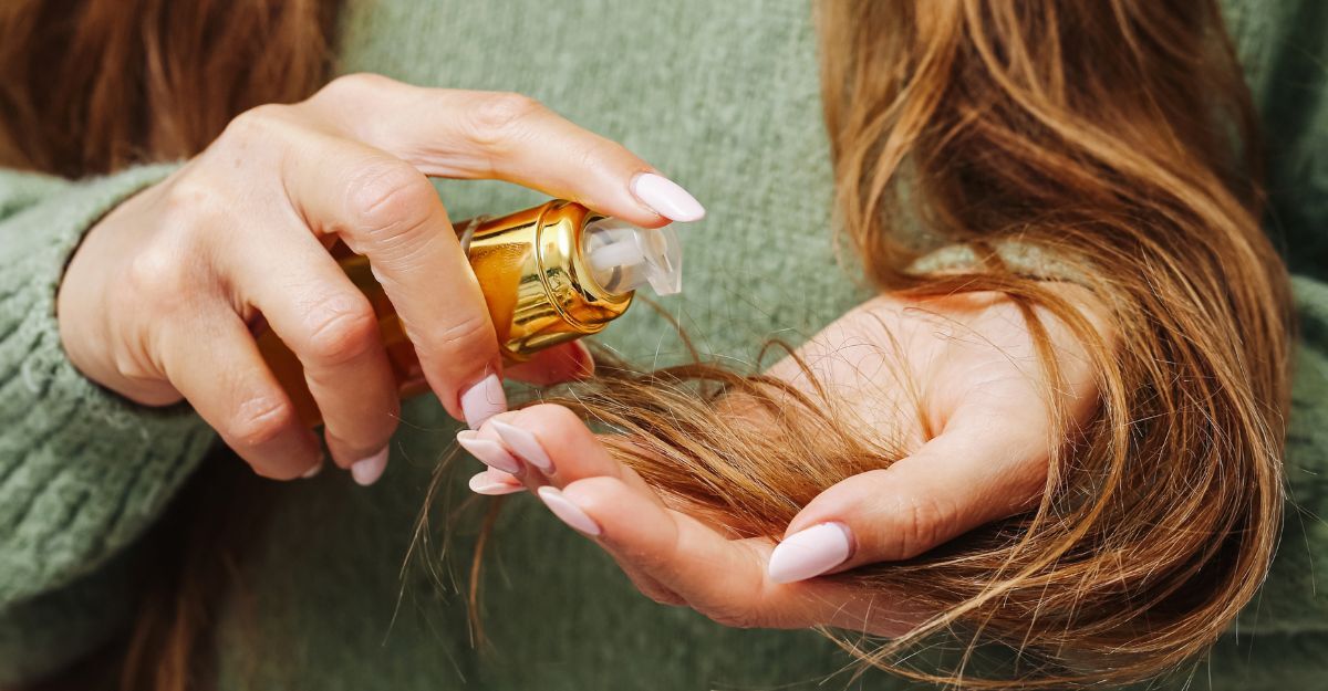 Primo piano di mani con ricostruzione unghie che dosano olio per capelli in un prodotto con erogatore in pump