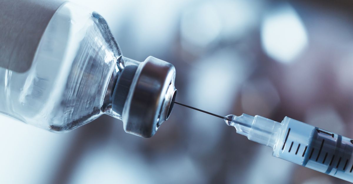 Primo piano di una siringa che estrae un liquido da una fiala di vetro.