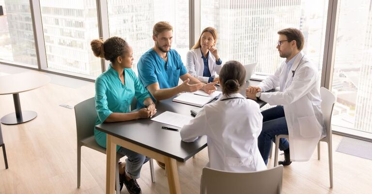 Gruppo di medici che discute fra di loro in merito alle novità in ambito medico in sala riunioni
