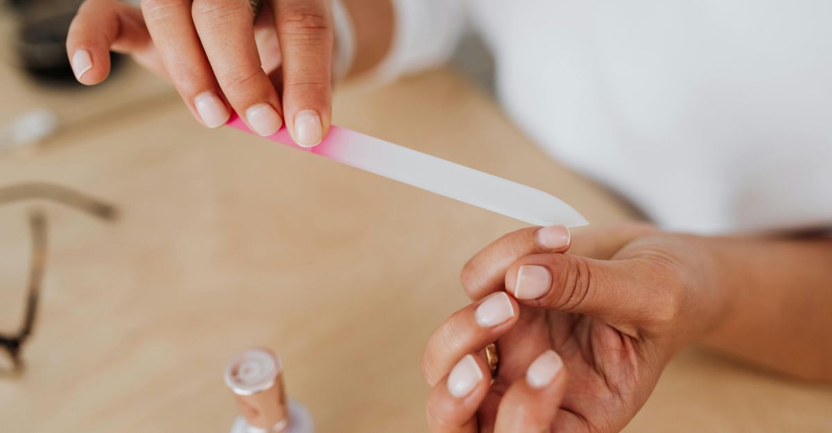 Primo piano di una donna dalle unghie curate e con smalto nude che si lima le unghie