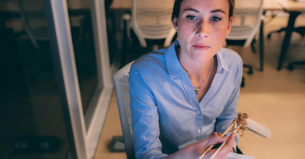 Donna che cena tardi in ufficio, abitudine che secondo uno studio può aumentare il rischio di osteoporosi.