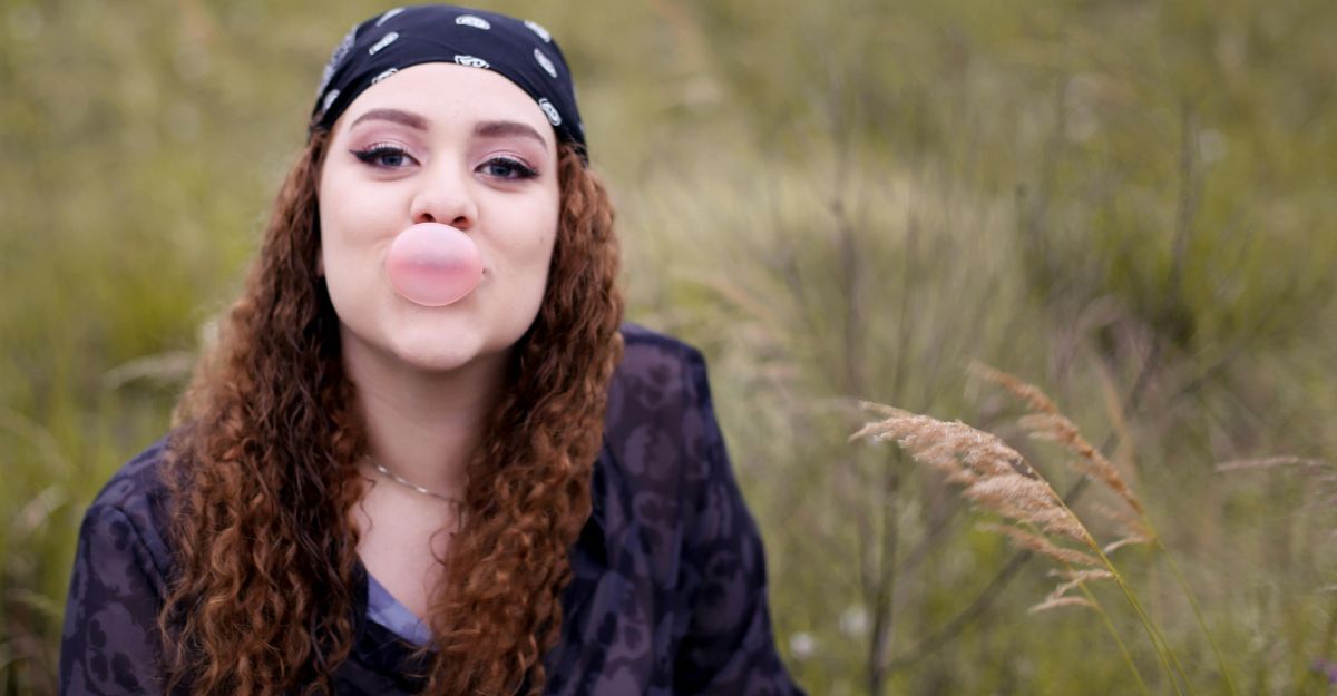 Giovane donna che mastica una gomma da masticare con dolcificanti artificiali e fa una bolla