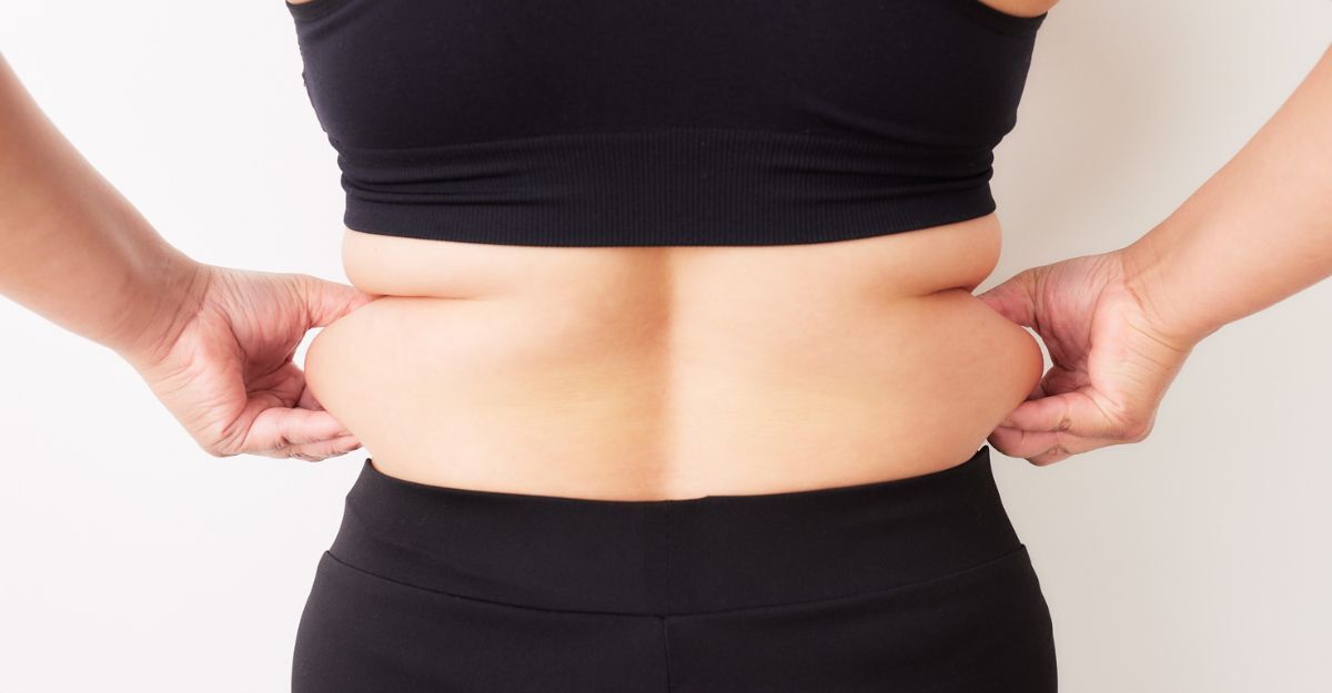 Una donna mostra il grasso addominale.