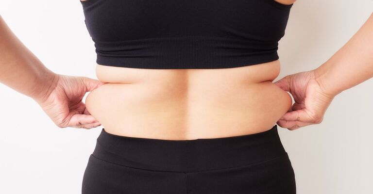Una donna mostra il grasso addominale.