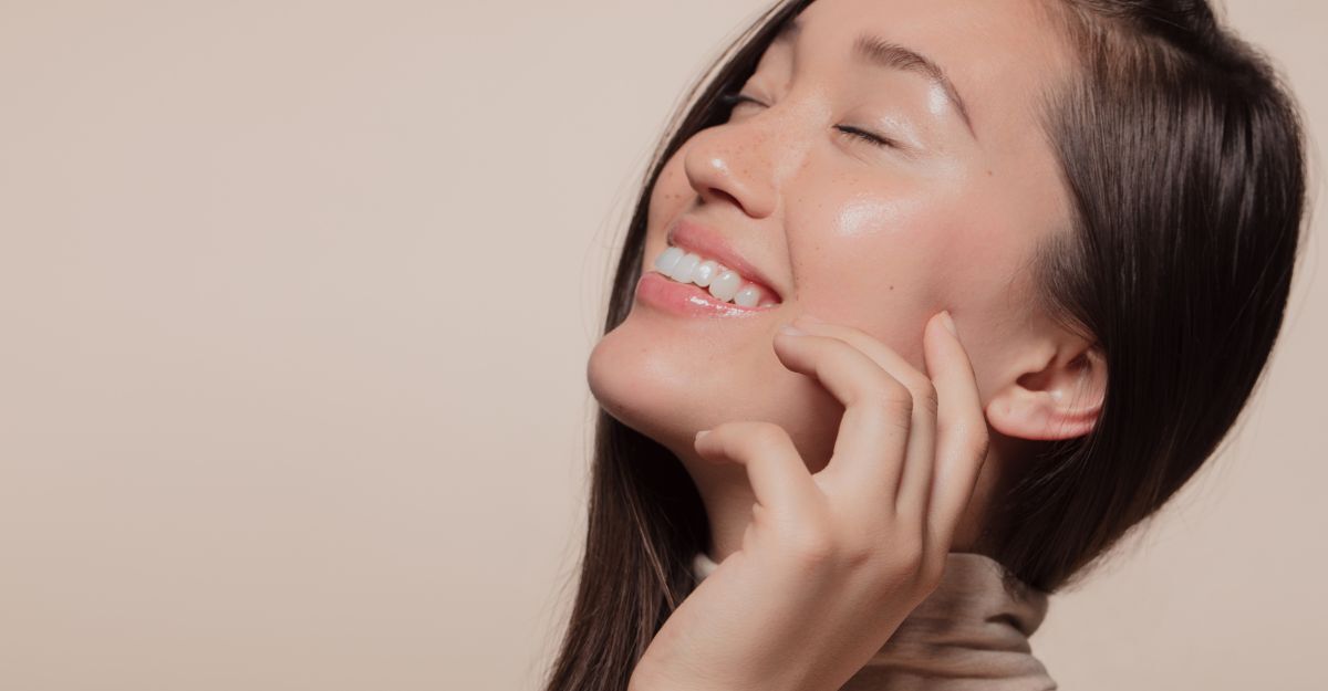 Una donna sorridente al sole mette un siero sul viso.