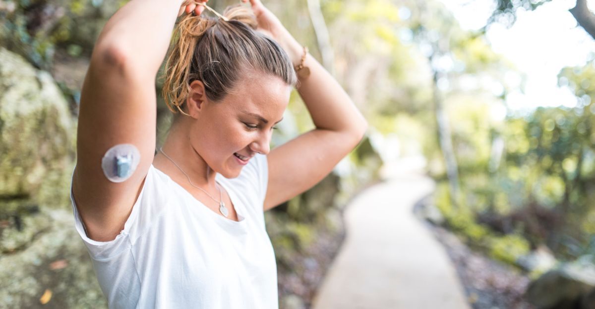 Donna giovane con sensore per monitoraggio glicemico sul braccio mentre si allena all’aperto, simbolo di prevenzione e gestione del diabete.