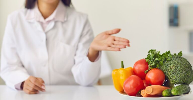 Una nutrizionista mostra un cesto di verdure.