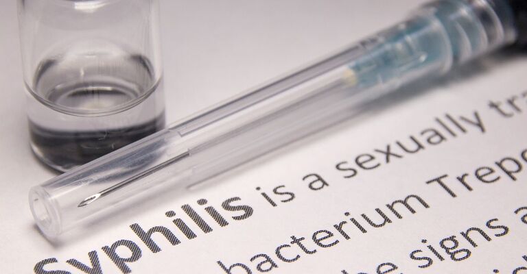 Siringa con farmaco e testo sulla sifilide, infezione sessualmente trasmissibile curata con penicillina