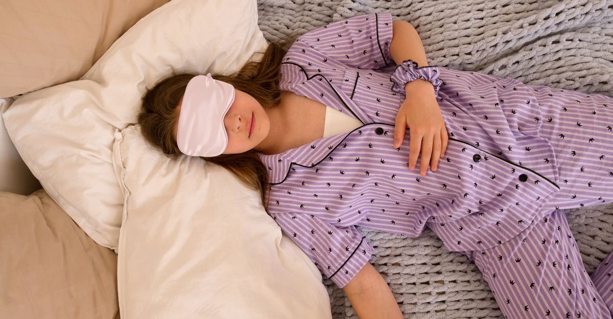 ragazza in pigiama lilla dorme nel letto, con la mascherina per gli occhi