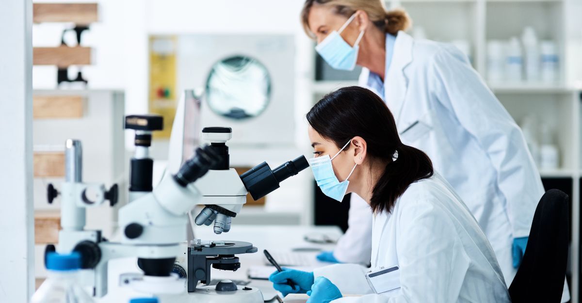 Due ricercatrici in laboratorio osservano campioni al microscopio durante uno studio sugli anticorpi per combattere diversi ceppi di influenza.